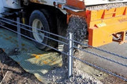 Truck dumping gravel over Biobarrier root barrier fabric installed along a roadway edge
