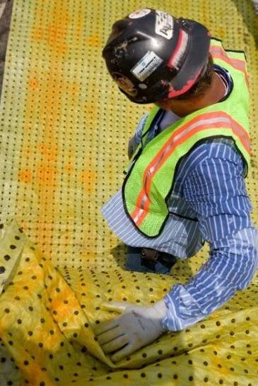 Close-up of a worker folding yellow Biobarrier root control fabric embedded with herbicide pellets
