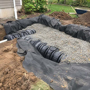 Non-woven drainage fabric lining a gravel bed around a septic distribution box installation
