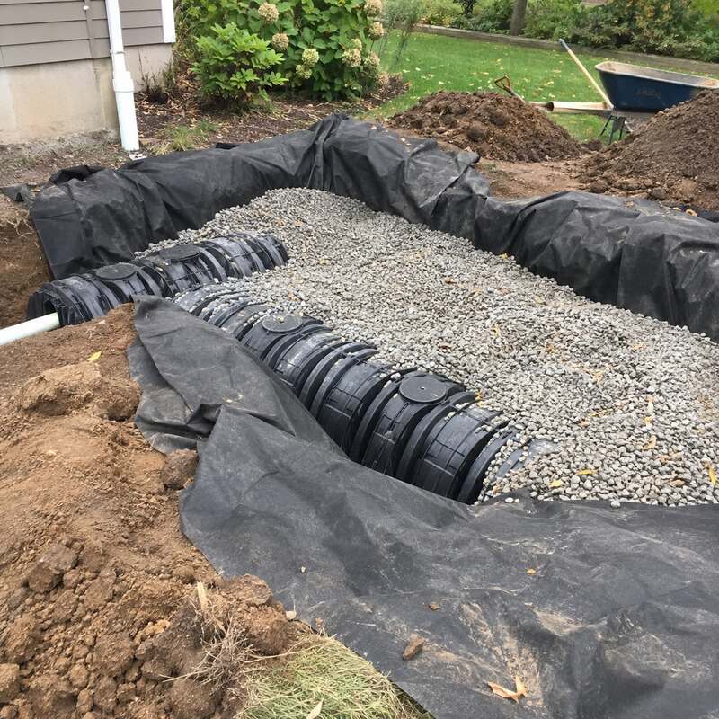 Non-woven drainage fabric lining a gravel bed around a septic distribution box installation
