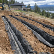 Drainfield fabric lining septic drain field trenches at a lakefront property with a septic service truck nearby
