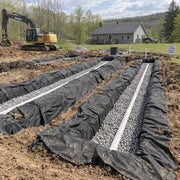 Spunbound drainfield fabric wrapping gravel-filled septic leach field trenches with perforated pipe at a rural home
