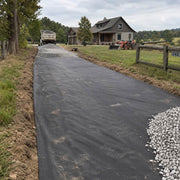 Driveway fabric installed on a farm driveway with a dump truck and red barn in the background
