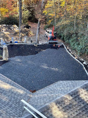 Aerial view of a large gravel paver driveway installation in progress next to a lodge

