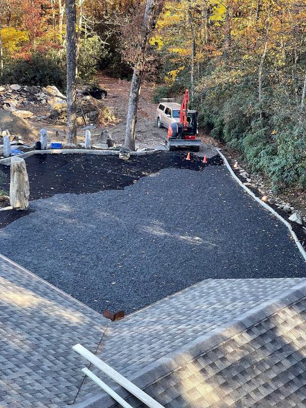 Aerial view of a large gravel paver driveway installation in progress next to a lodge
