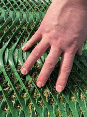 Hand pressing on Mudstop grass protection mesh to show its flexible texture
