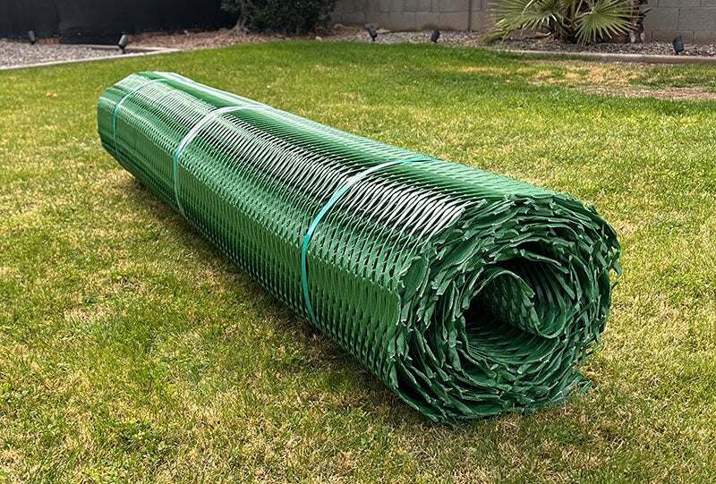 Rolled green Mudstop grass protection mesh product banded and staged on a lawn
