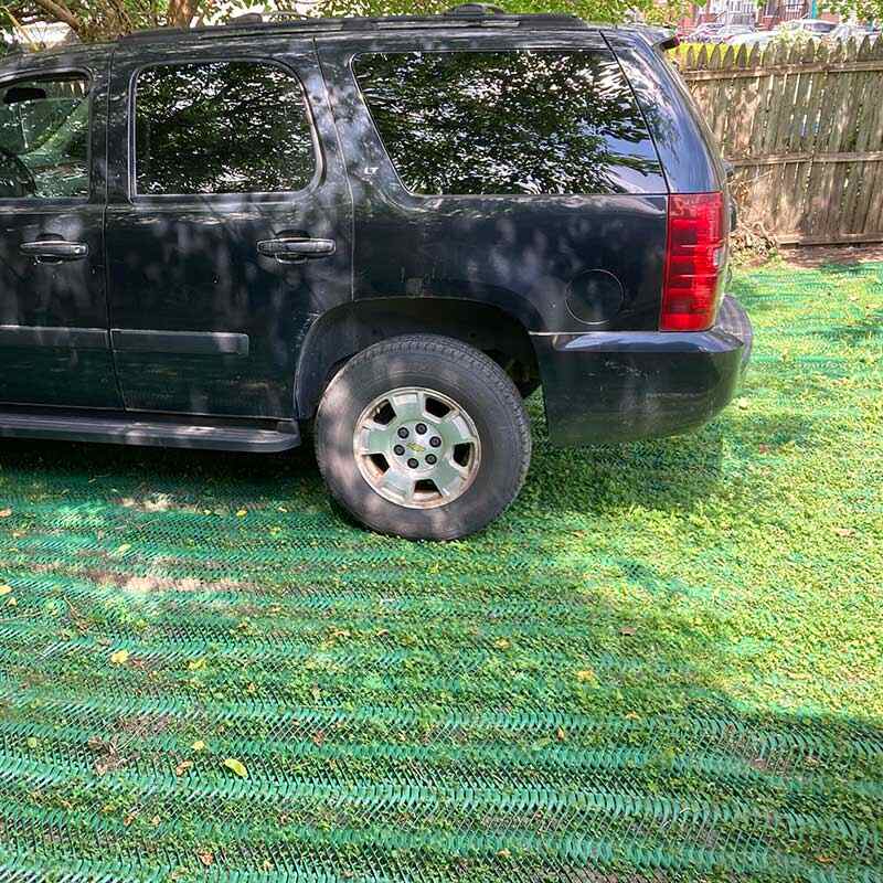 SUV parked on a lawn reinforced with Mudstop grass protection mesh, side view
