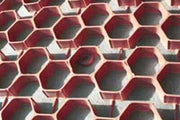 Close-up of NDS gravel paver grid in red, showing the hexagonal cell pattern over gravel
