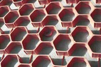 Close-up of NDS gravel paver grid in red, showing the hexagonal cell pattern over gravel

