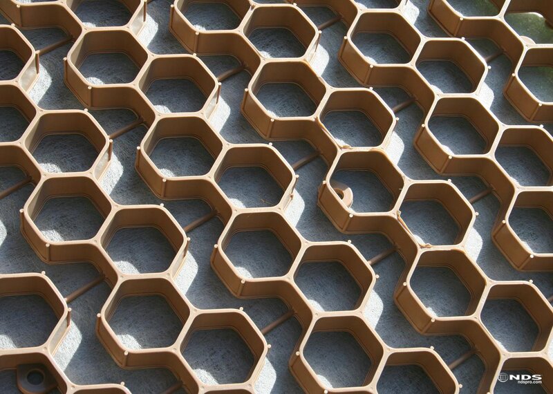 Close-up of NDS gravel paver grid in tan, showing the hexagonal cell pattern over geotextile fabric
