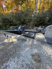 Workers installing NDS gravel paver grid panels with a dog supervising the driveway project
