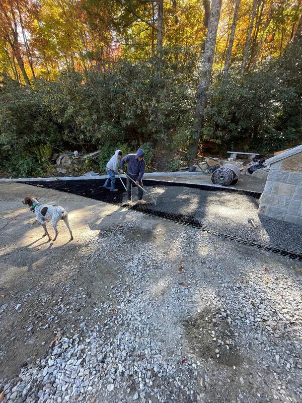 Workers installing NDS gravel paver grid panels with a dog supervising the driveway project
