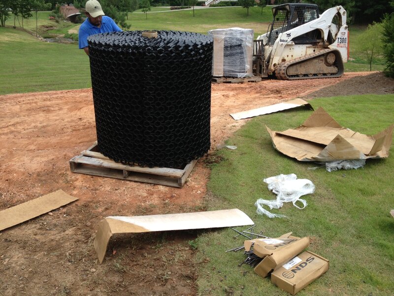 Large roll of NDS gravel paver grid delivered on site next to a skid steer loader
