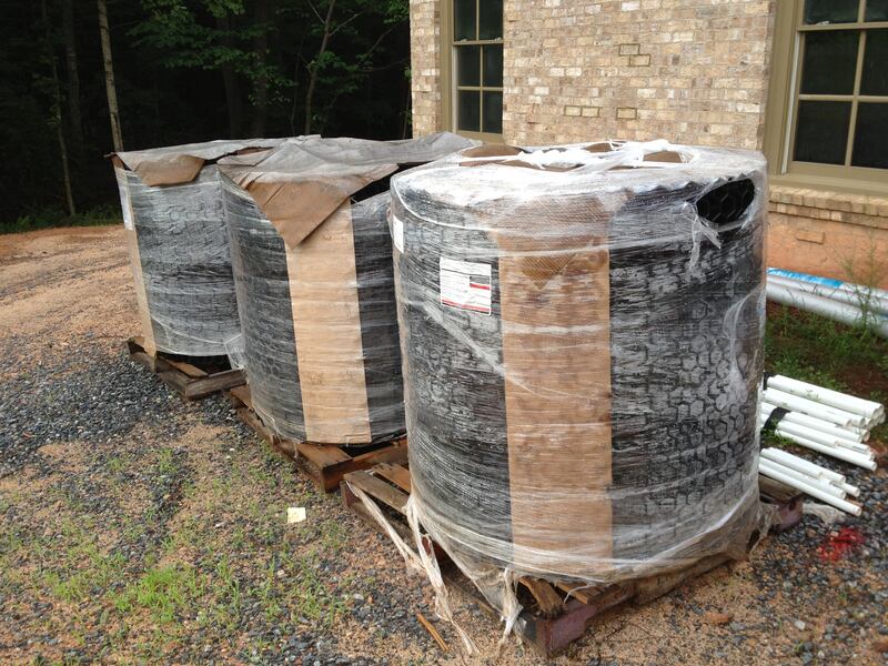 Pallets of rolled NDS gravel paver grid staged at a jobsite next to a brick house
