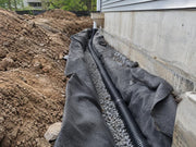 Non-woven fabric lining a foundation drain trench with gravel and perforated pipe
