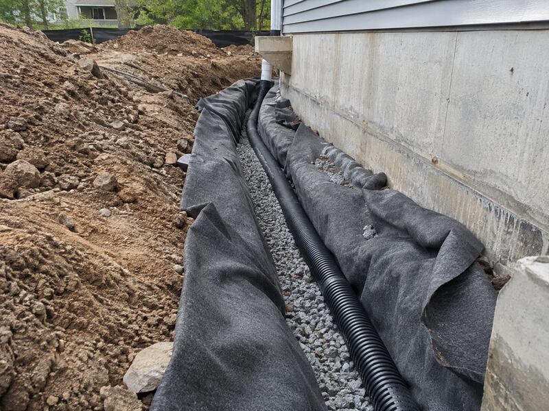 Non-woven fabric lining a foundation drain trench with gravel and perforated pipe
