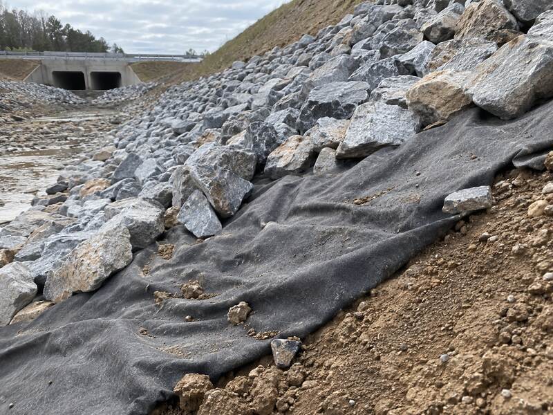 Non-woven fabric placed beneath rip rap stone in a drainage channel near a culvert
