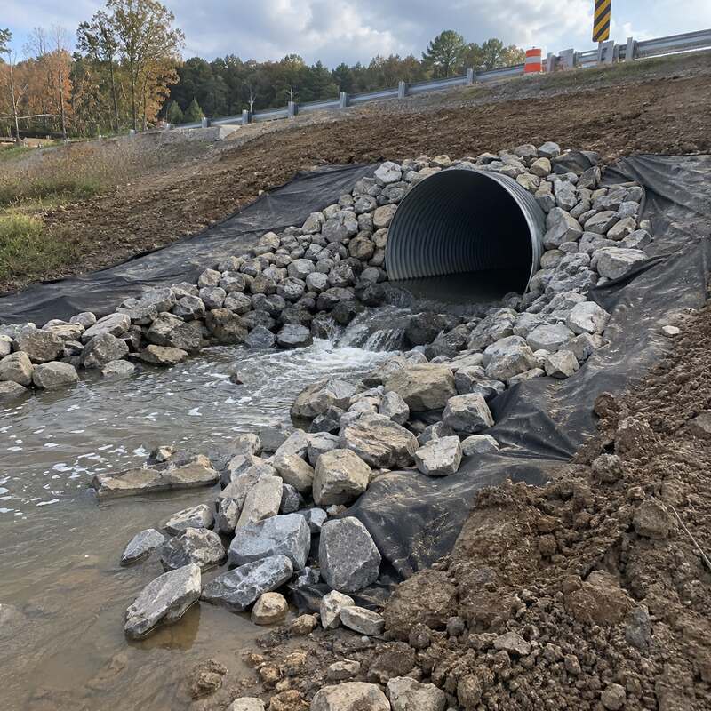 Non-woven geotextile fabric beneath rip rap stone at a culvert outlet along a roadside drainage channel
