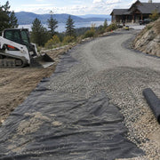 Non-woven geotextile fabric laid beneath a gravel driveway on a mountainside property overlooking a lake
