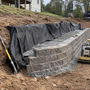 Non-woven geotextile fabric wrapping gravel backfill behind a segmental block retaining wall under construction
