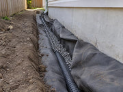 Non-woven soil filter fabric wrapping gravel and drain pipe along a house foundation
