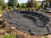 Pond underlayment fabric being installed in an excavated backyard pond basin
