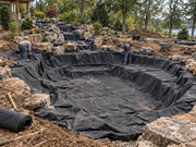 Pond underlayment fabric installed in a boulder-terraced pond basin overlooking a lake
