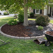 Weed barrier fabric installed in a circular tree ring bed edged with stone pavers
