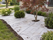 White ground cover fabric installed around a Japanese maple and shrubs in a foundation planting bed
