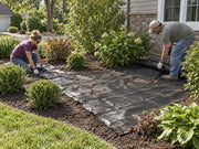 Workers cutting woven ground cover fabric around a newly planted tree in a brick-edged bed
