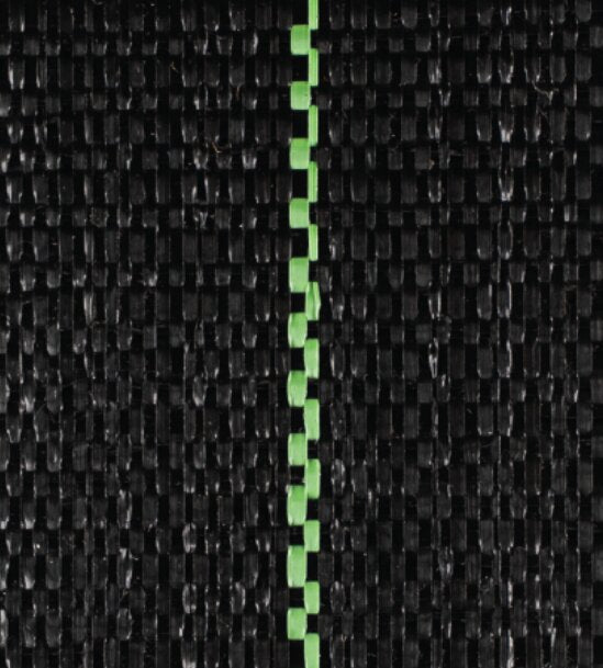 Close-up of black woven ground cover fabric texture with a green woven marking line
